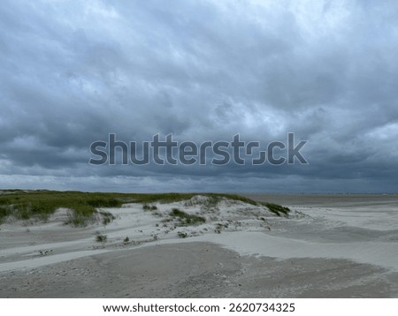 Storm clouds over the sandy beach with grassy dunes near Sankt Peter-Bad, Schleswig-Holstein, Germany, July 2024