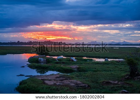 Storm clouds over the water with the sunset over the lake, orange sunlight, dramatic sky with clouds. Beautiful reflections in water