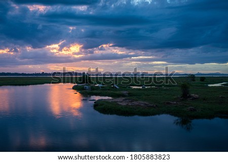 Storm clouds over the water with the sunset over the lake, orange sunlight, dramatic sky with clouds. Beautiful reflections in water