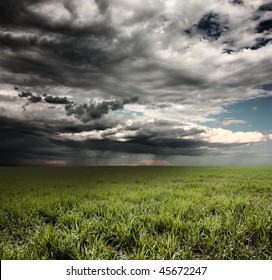 Storm Clouds With Rain Over Meadow With Green Grass