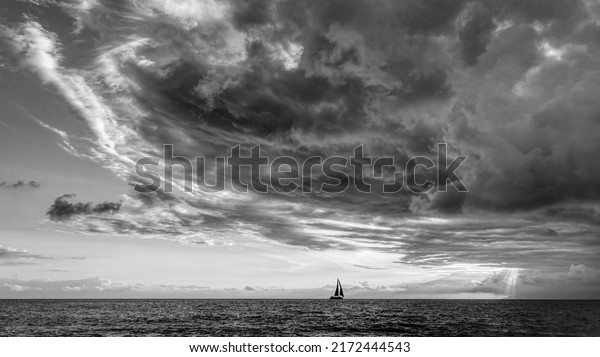 A Storm Is Looming Overhead As A
Small Boat Moves Toward The Shining Light Black And
White