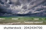 A storm with a rainbow on the Gulf of Mexico with a boat going by and the surf in the foreground.