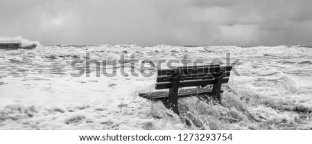 STORM AT SEA - A bench flooded by storm waves on a sea beach in Kolobrzeg
