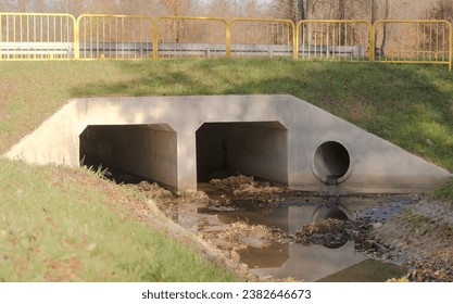 Storm sewer - a concrete culvert under the street.Storm sewer (and drainage) also called the "Stinky River". Concrete culvert (bridge) under the road - street in the outskirts of the city. - Powered by Shutterstock