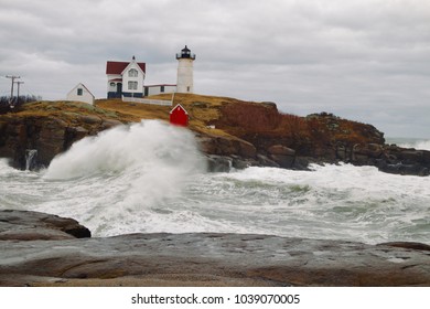 Nor’easter Storm Waves Crash Along The Rocks At The Nubble Lighthouse In York Maine On An Overcast Day.