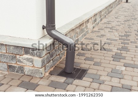 stormwater pipe on facade with rainwater drainage into the drainage system with a sewer manhole grill.
