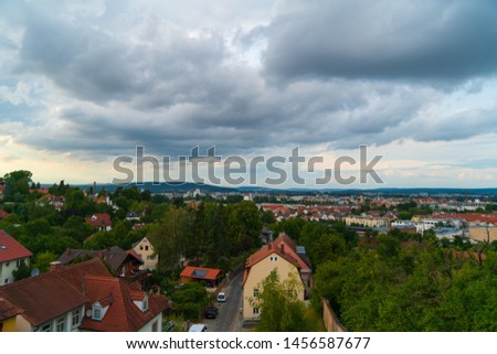 Stormy clouds over houses and forest area at sunset
