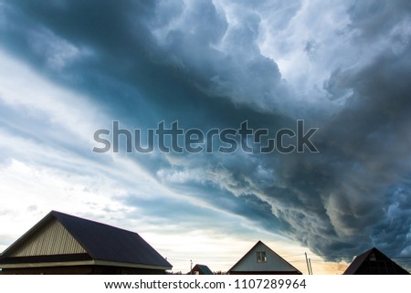 Stormy clouds over a small town with one-story houses. Formation of a hurricane