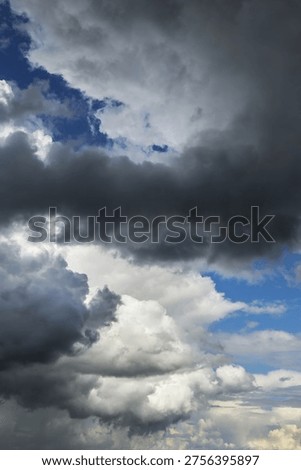 Stormy cloudy dramatic sky with dark rain grey cumulus clouds and blue sky background texture