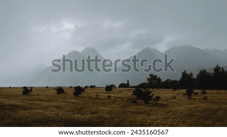 Stormy foggy sky and clouds cover mountain peaks and countryside