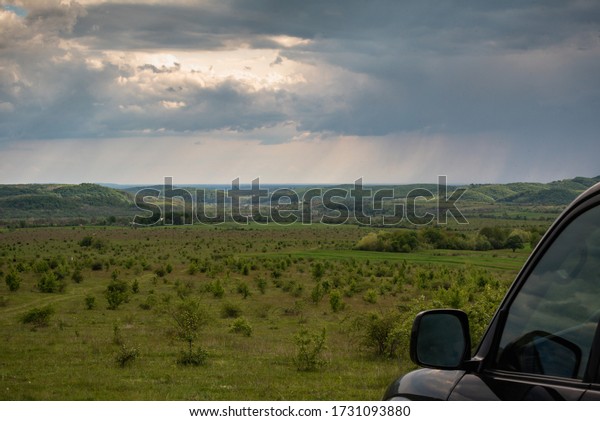 Stormy landscape on\
the plain with an SUV
