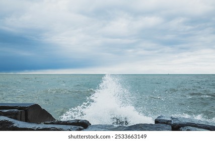 Stormy ocean waves crash against rugged rocky coast under cloudy sky - Powered by Shutterstock