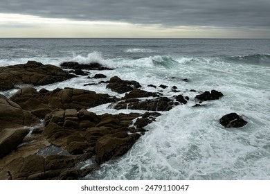 Stormy Ocean Waves Crashing on Rocky Shore with Seaweed and Cloudy Sky. - Powered by Shutterstock