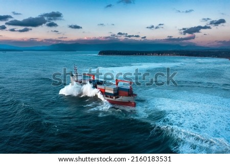 Stormy sea with Container ship delivering cargo at sunset