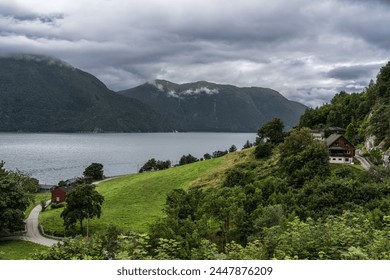 Stormy Skies Over Tingvollfjorden Near Ålvundeid Village. Overcast weather looms above the tranquil fjord with rural Norwegian houses nestled in lush greenery. In Møre og Romsdal county Norway - Powered by Shutterstock