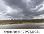 A stormy sky with a few clouds and a road with rain. Scene is gloomy and overcast