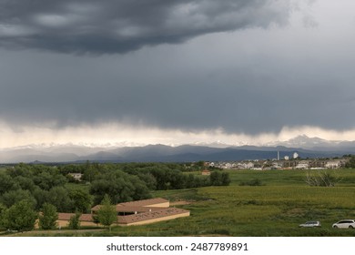 A Stormy Sky Over Green Fields and Snow-Capped Mountains in Longmont, Colorado - Powered by Shutterstock