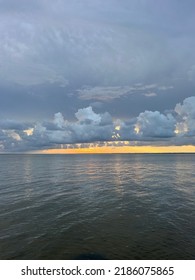 Stormy Sunset Skies With A Low Band Of Bright Orange Over Calm Bay Water