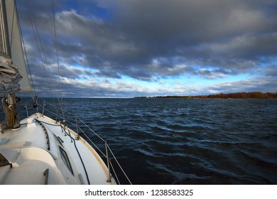 Stormy Weather On The Baltic Sea. White Yacht Sailing. A View From The Deck To The Bow And Sails, Close-up. Port In The Background. Latvia