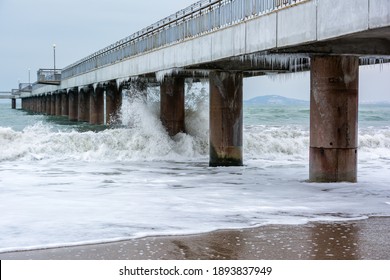 Stormy winter Black Sea, Burgas bay, Bulgaria. Winter landscape. Icicles hanging on bridge. Crashing waves.