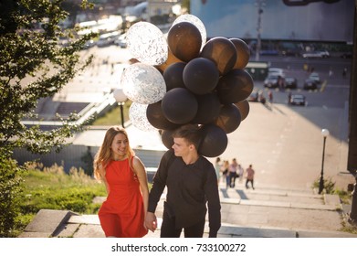 Story Of A Cute Loving Couple With Black Balloons, Coming Up The Stairs And Smiling