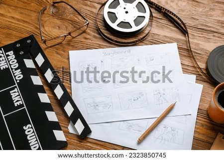 Storyboard with movie clapper and film reel on wooden background