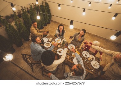 Storytelling footage of a multiethnic group of people dining on a rooftop. Family and friends make a reunion at home - Powered by Shutterstock