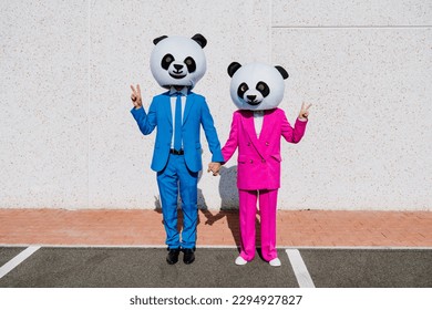 Storytelling image of a couple wearing giant panda head and colored suits. Man and woman making party in a parking lot.