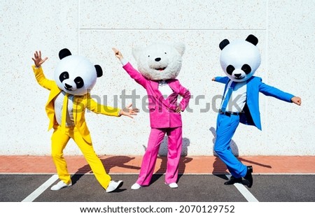 Storytelling image of a couple wearing giant panda head and colored suits. Man and woman making party in a parking lot.