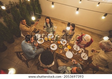 Storytelling image of a multiethnic group of people dining on a rooftop. Family and friends make a reunion at home. 