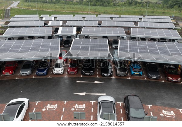 STOURTON, LEEDS, UK - MAY 16, 2022.  Aerial view\
above innovative solar panels located on a car parking lot rooftops\
making good use of small space in a city and charging electric\
cars