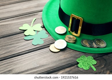 St.Patrick's Day. Paper clover leafs with coins and hat on wooden table - Powered by Shutterstock