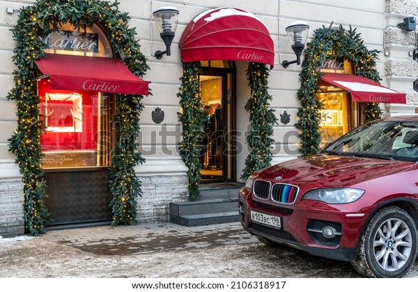 St.Petersburg, Russia. 18.12.2021 Cartier
shop window display. Cartier boutique view and lonely red bmw car
parked nearby. Christmas
decoration.