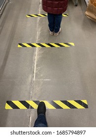 St.Petersburg / Russia - March 2020: Black and yellow tape markers in a supermarket indicating safe distance in a line during coronavirus outbreak