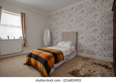 Stradishall, Suffolk, England - June 1 2017 Furnished Bedroom With Feature Wallpaper Wall And Brightly Coloured Blanket.