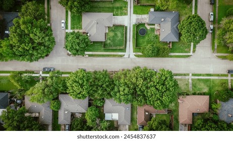 Straight aerial view suburban house in lush green tree, large wooden fenced backyard suburbs Dallas, Texas, detached residential single-family home with parked cars on quite street, subdivision. USA