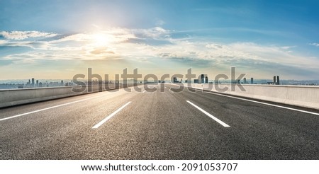 Straight asphalt road with modern city skyline and buildings