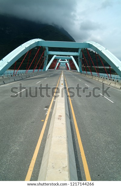 Straight bridges, highways, and\
mountains leading to the mountains are covered by gray\
clouds.