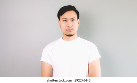 Straight Face. An Asian Man With White T-shirt And Grey Background.