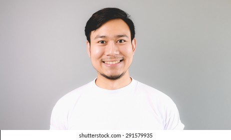 Straight Happy Face. An Asian Man With White T-shirt And Grey Background.