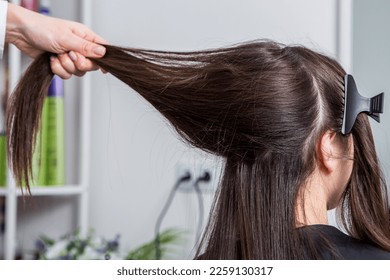 A straight healthy brunette hair that has undergone the hair straightening procedure. Hair straightening in the beauty salon. Hair care. - Shutterstock ID 2259130317