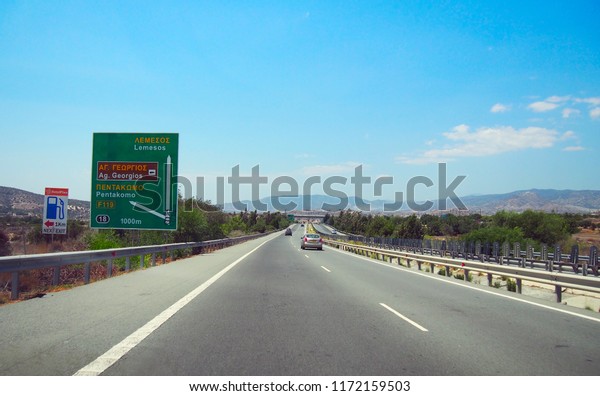 Straight motorway in Cyprus with road sign. Bright\
sunny summer day