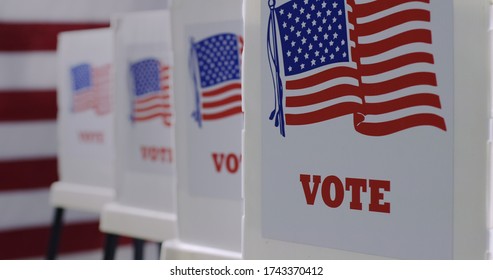 Straight on row of voting booths at polling station during American election. US flag in background. - Shutterstock ID 1743370412