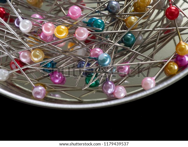 Straight pins for sewing.\
Colorful pins on a shiny silver background. Top view image with\
copy space. 