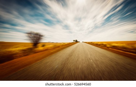 Straight Road Goes To Horizon On Background Of Ble Sky And Golden Wheat Field.  Motion Blur Effect .