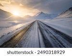 Straight road in southern Iceland at sunset, in winter, icy slippery road with mountains visible and cloudy sky, Route 1 Ring Road in Iceland