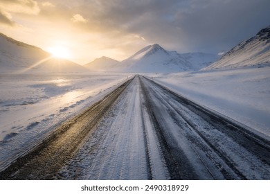 Straight road in southern Iceland at sunset, in winter, icy slippery road with mountains visible and cloudy sky, Route 1 Ring Road in Iceland - Powered by Shutterstock