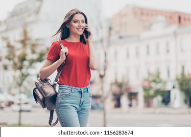 Straight-haired young beautiful smiling caucasian girl wearing casual red t-shirt and jeans outside, traveling abroad, chatting on cell phone - Powered by Shutterstock