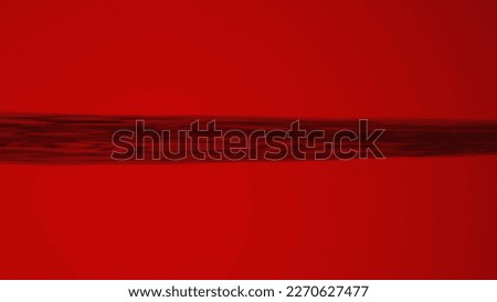 A strand of hair stretched out in a horizontal lines on a red background. Macro shot of bunch of hair. Texture of a human hair. Threads, strings, hair strand under a microscope or a magnifying loupe.