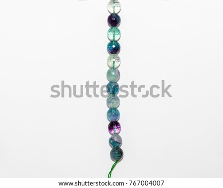 a strand of medium sized round multi colored beads on a green string